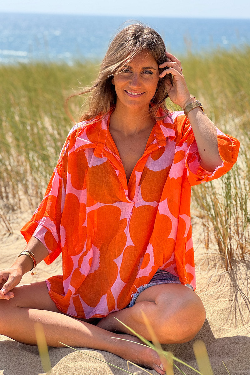 Blusa ligera de voile de algodón rosa con estampado de grandes flores naranjas y cuello camisero en pico.