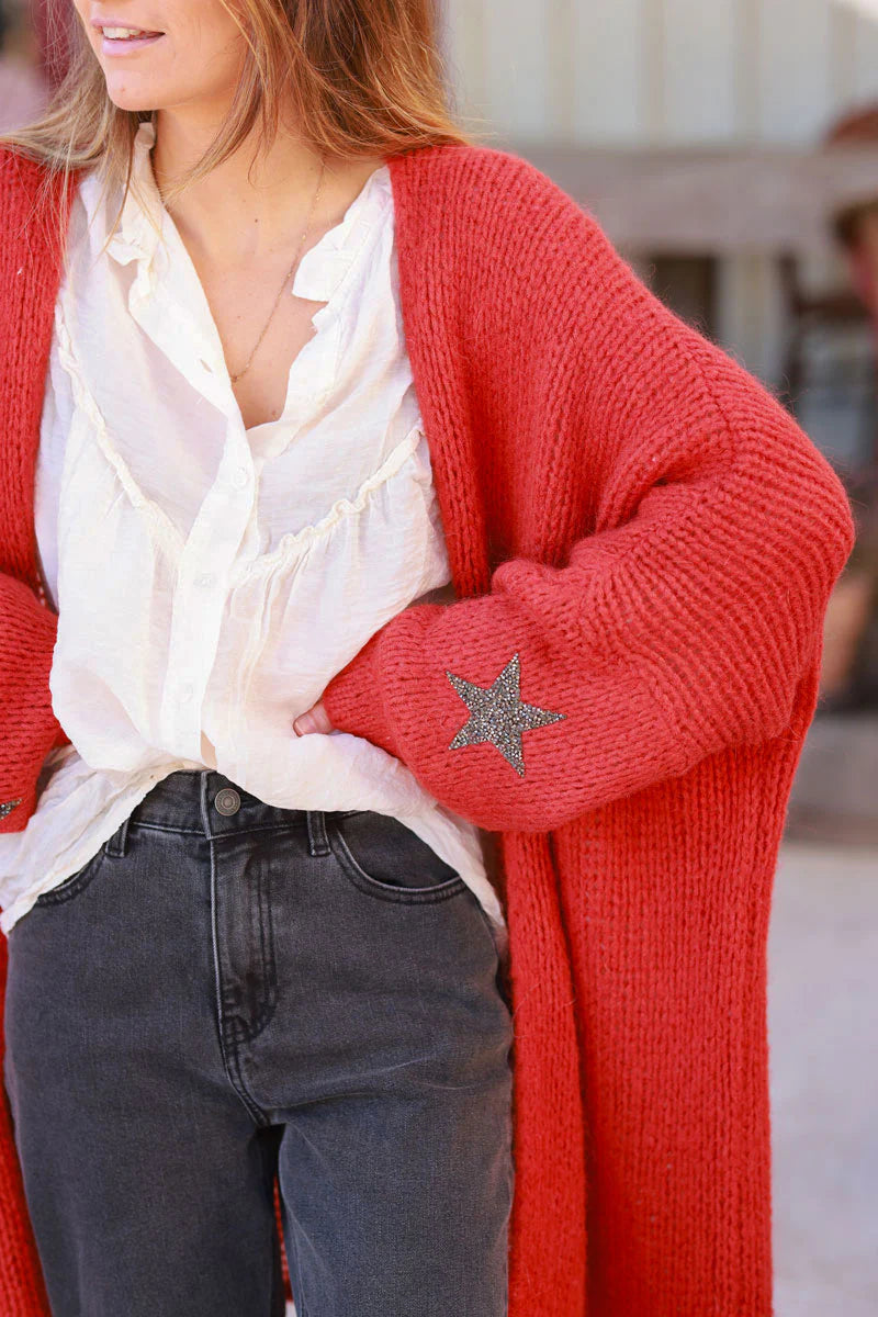 Cárdigan rojo anaranjado de longitud media con mangas gruesas con diamantes de imitación en forma de estrella.