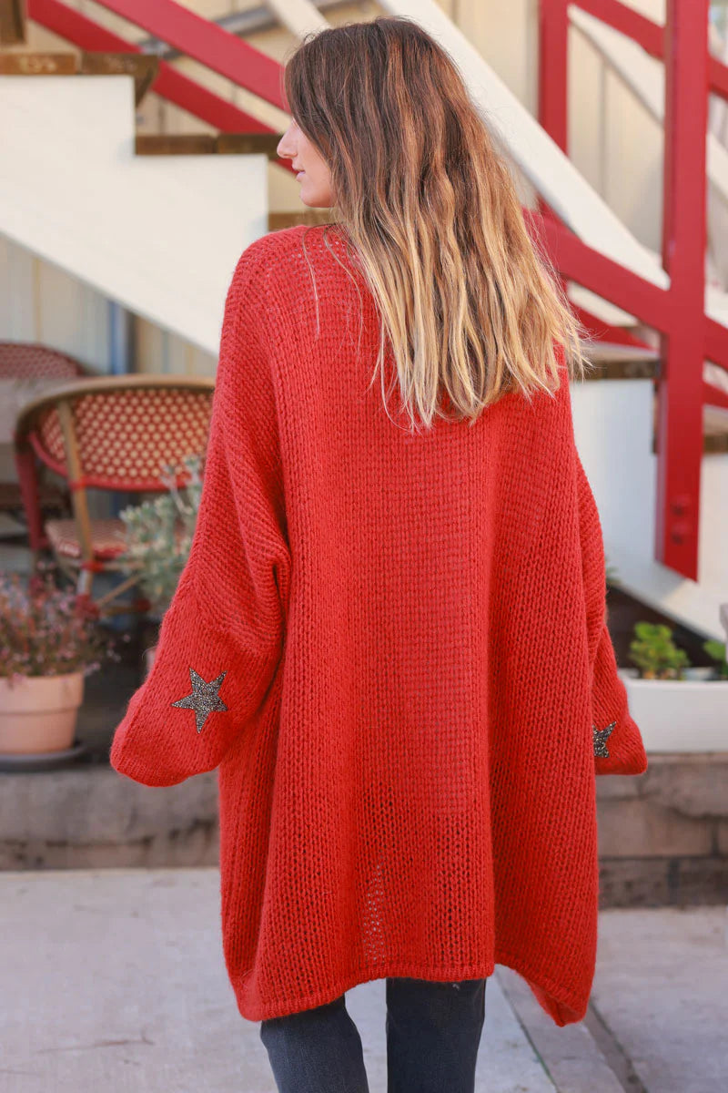 Cárdigan rojo anaranjado de longitud media con mangas gruesas con diamantes de imitación en forma de estrella.