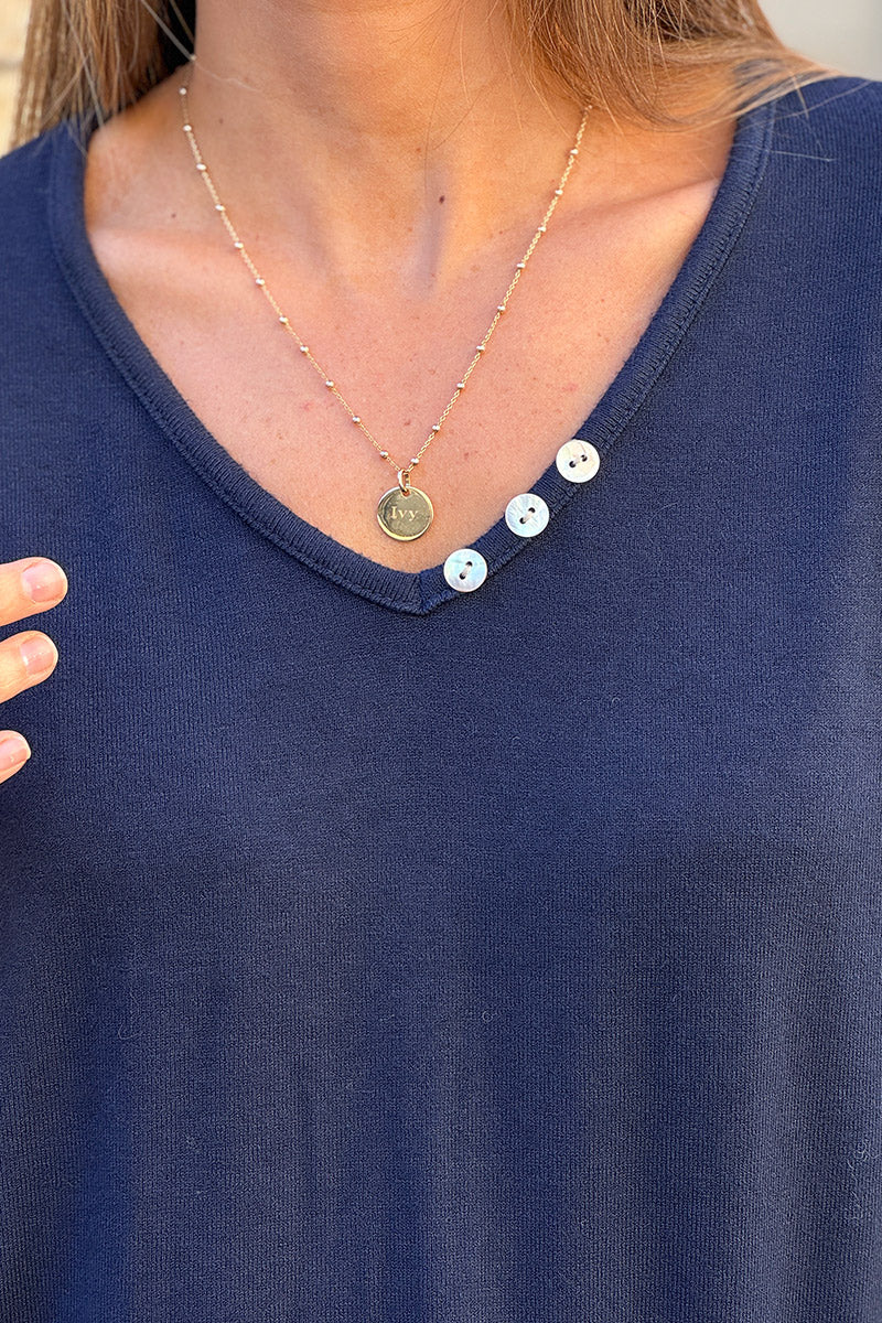 Suéter pequeño azul marino de punto suave con cuello de pequeños botones de nácar.
