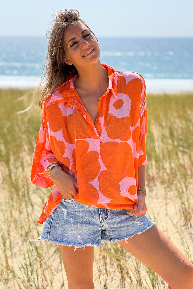 Blusa ligera de voile de algodón rosa con estampado de grandes flores naranjas y cuello camisero en pico.