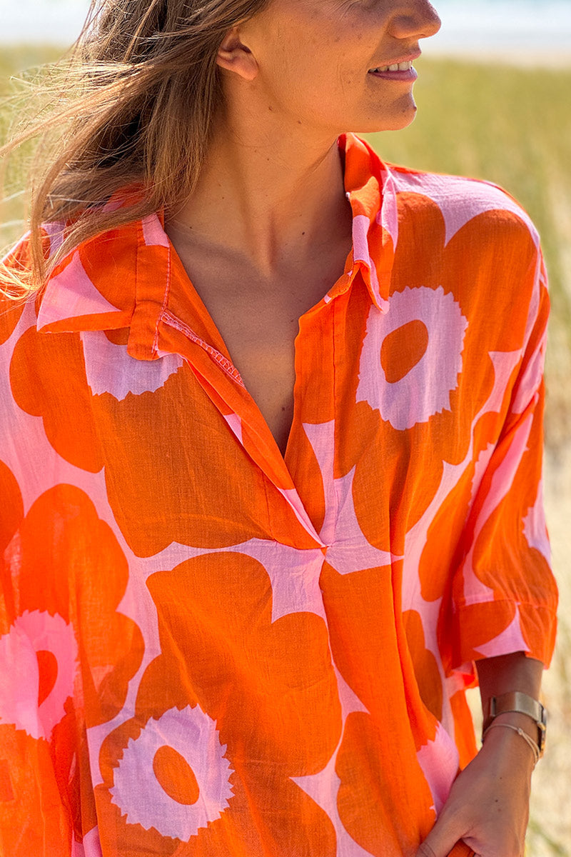 Blusa ligera de voile de algodón rosa con estampado de grandes flores naranjas y cuello camisero en pico.