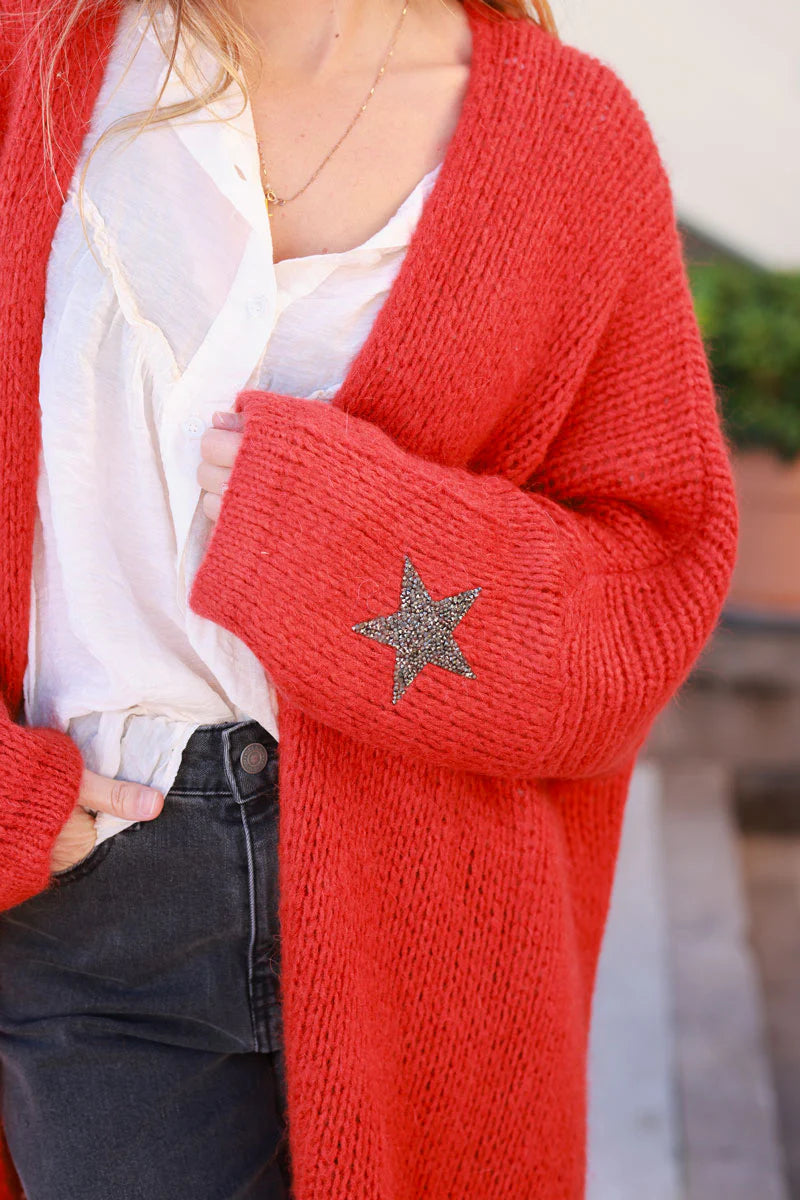 Cárdigan rojo anaranjado de longitud media con mangas gruesas con diamantes de imitación en forma de estrella.
