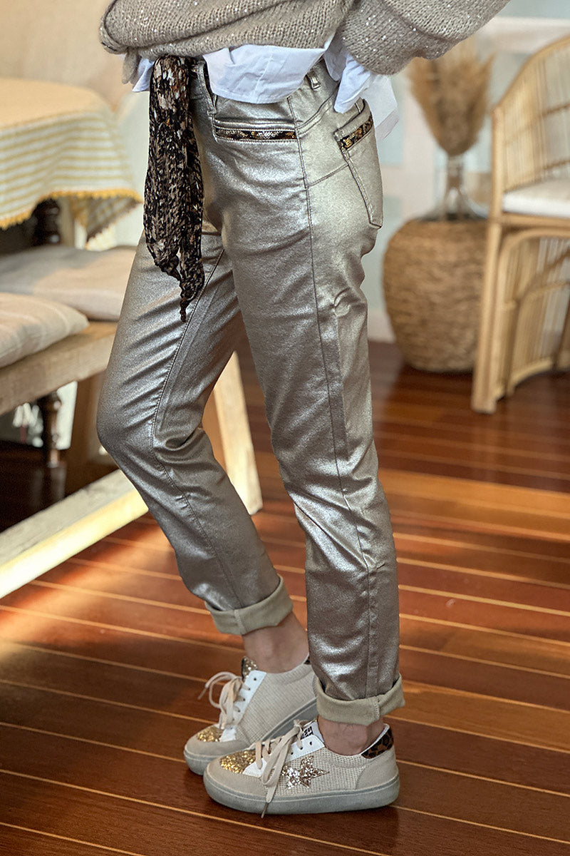 Pantalón slim fit con acabado efecto aceite, forrado en dorado con ribete de lentejuelas y pañuelo estampado.